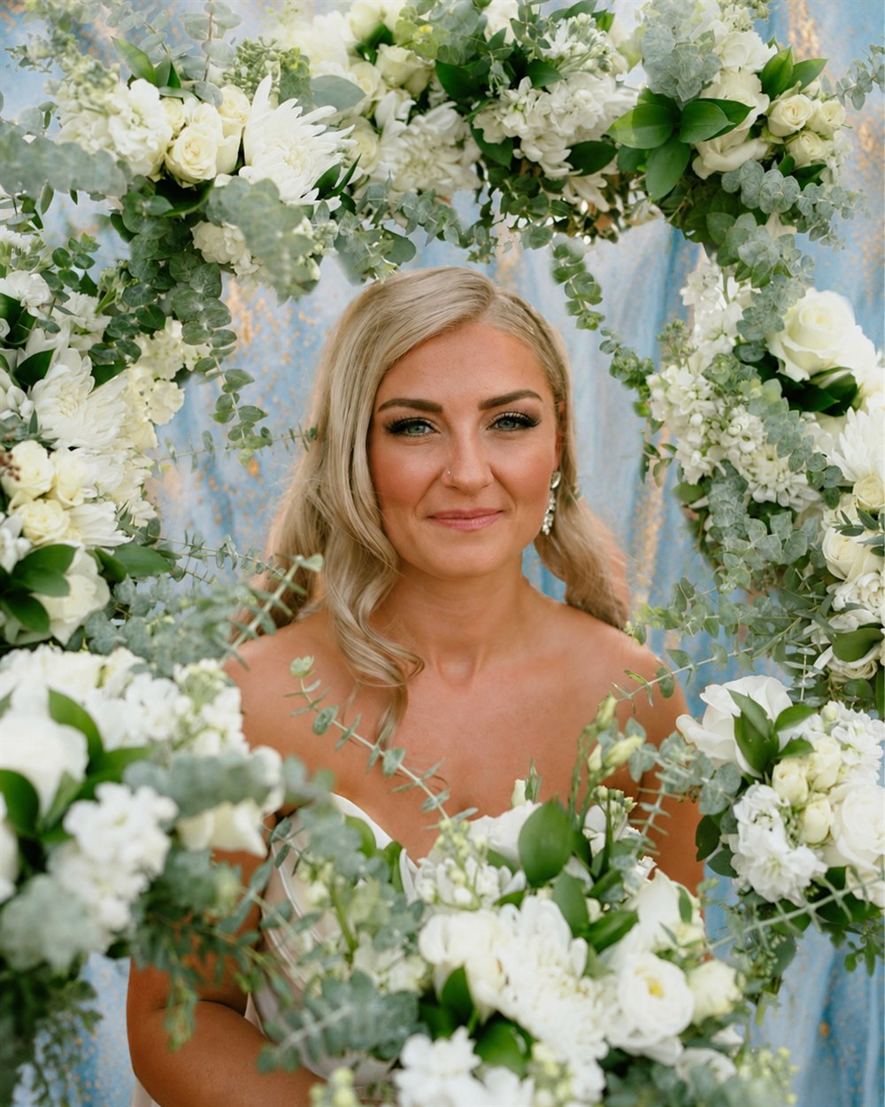 Bride framed by a white floral wedding backdrop
